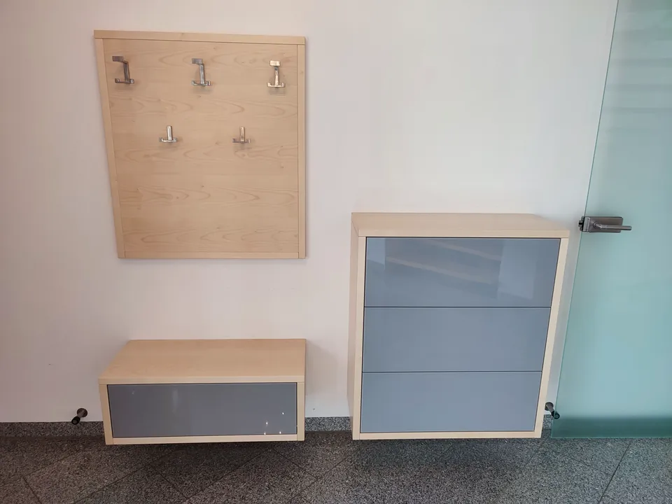 Garderobe aus hellem Holz mit Hakenpaneel, Sitzbank und Kommode mit grauen Fronten
